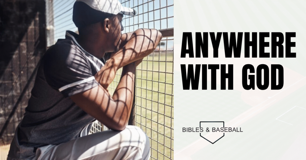 Baseball player sitting in the dugout, gazing toward the field, reflecting on faith and finding peace anywhere with God.