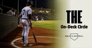 Baseball player waiting in the on-deck circle during a night game under stadium lights, focused on the upcoming at-bat.